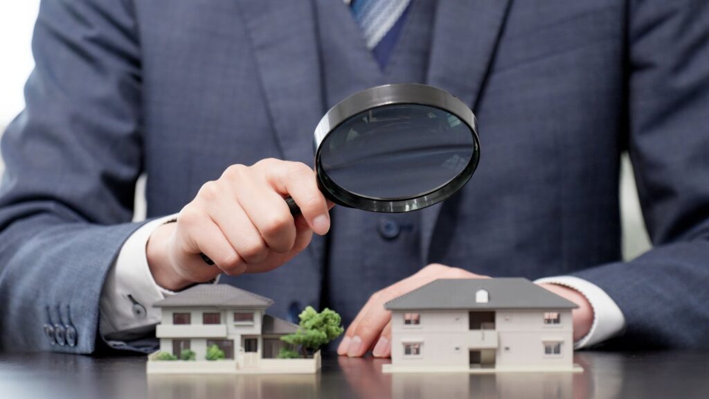 住宅模型と虫眼鏡を使って住宅の査定をするイメージ